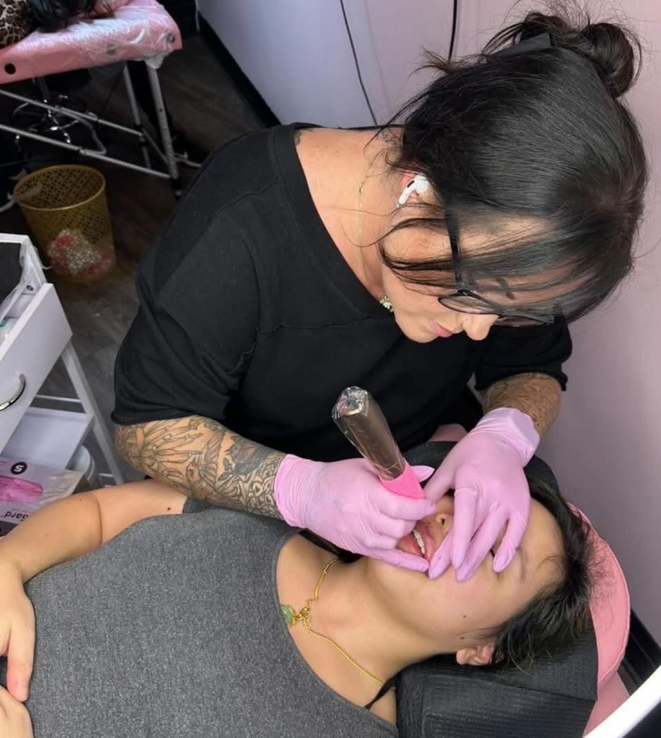 Christine at work, applying permanent makeup to a client under a ring light.