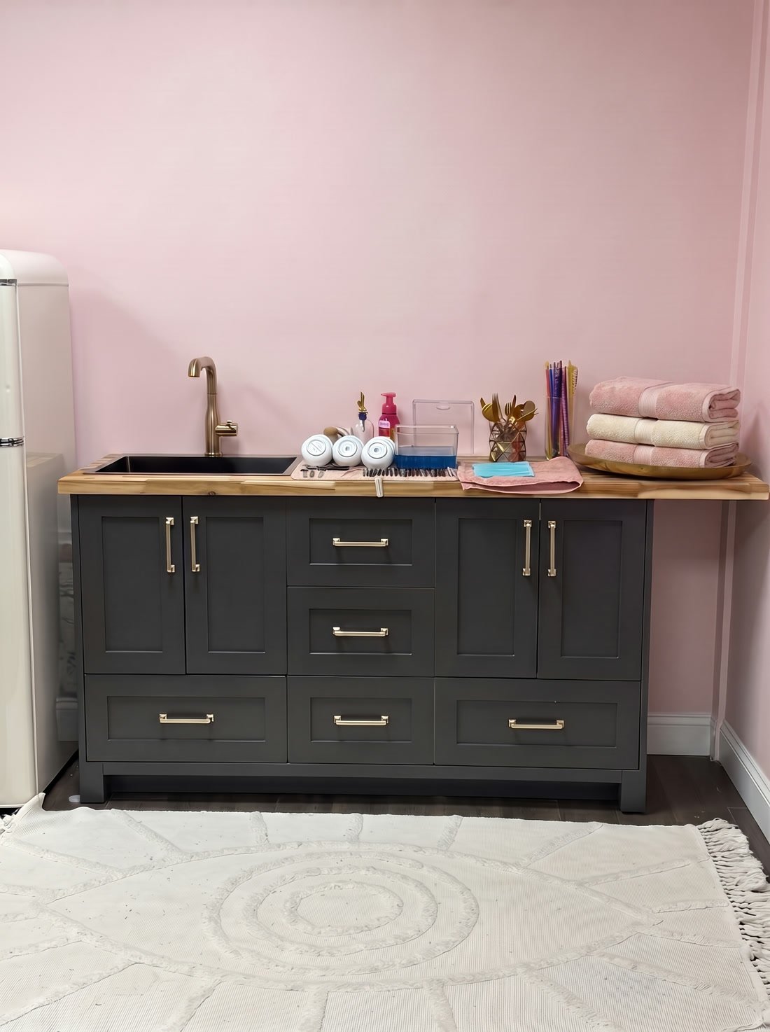 The wash-up station: a black cabinet with a brass tap, tools laid out to dry, and fresh folded towels.