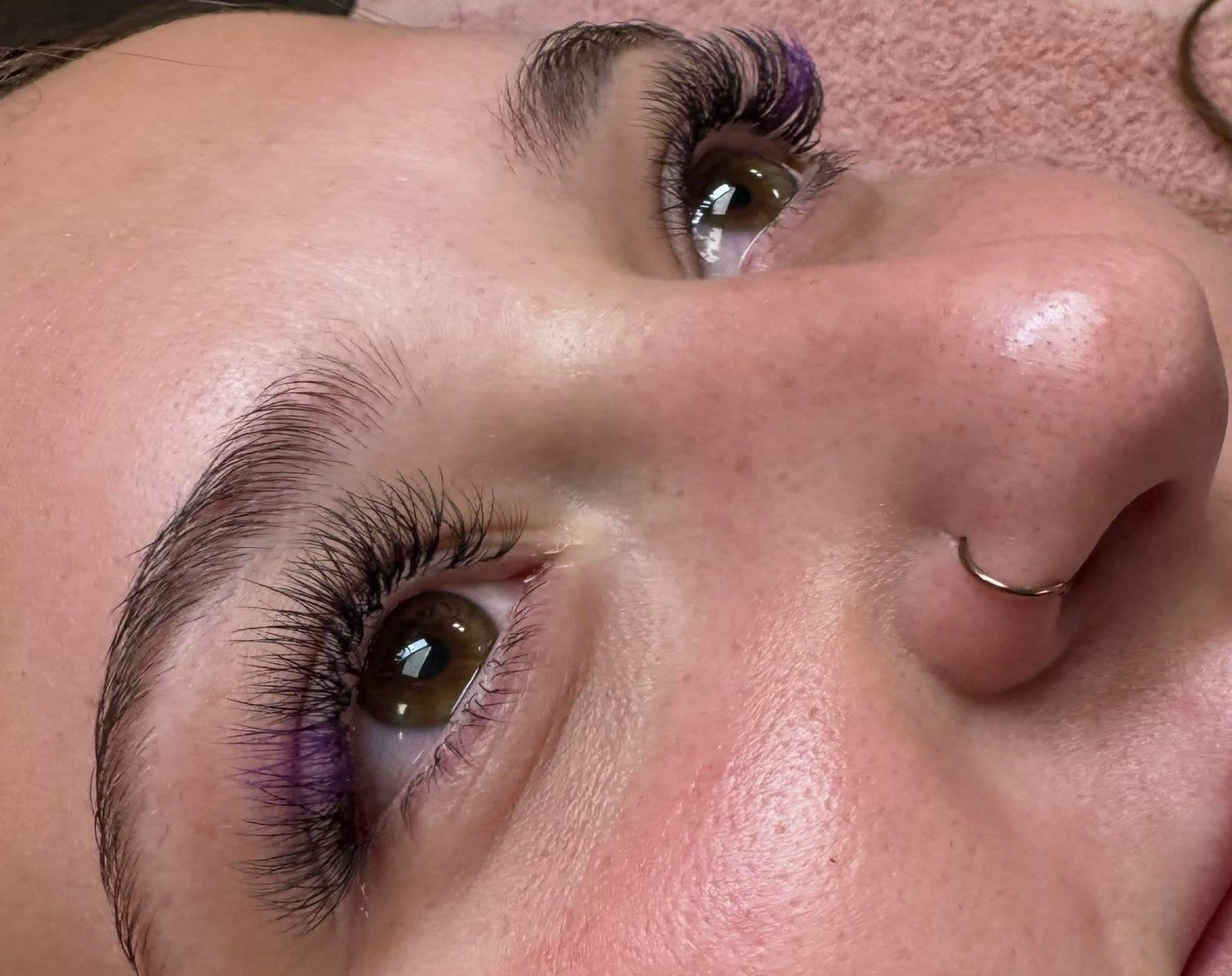 Lash extensions with violet tips at the outer corners, both eyes.